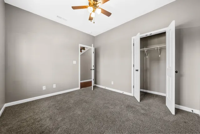 an empty room with closet and a chandelier fan
