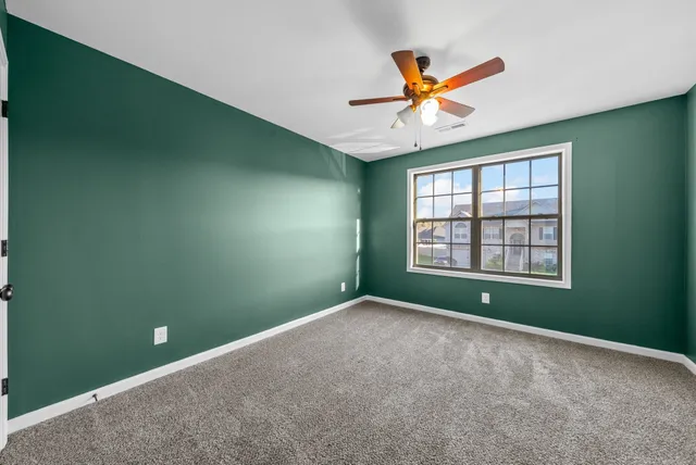 a view of an empty room with window and ceiling fan