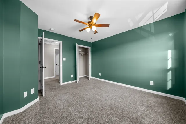 an empty room with closet and a chandelier fan