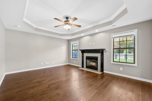 an empty room with windows fireplace and wooden floor