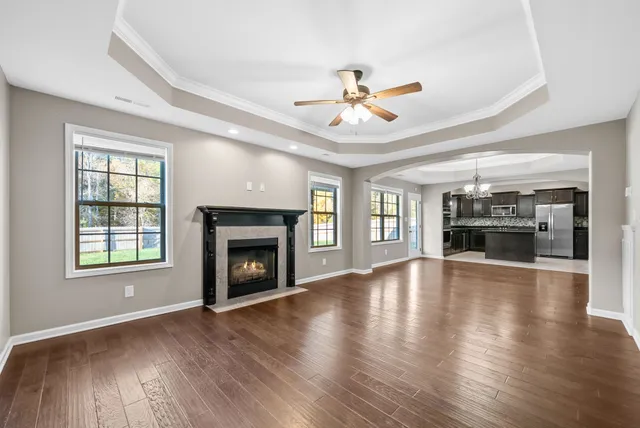 an empty room with wooden floor fireplace and windows