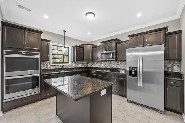 a kitchen with stainless steel appliances granite countertop a refrigerator a sink and a stove
