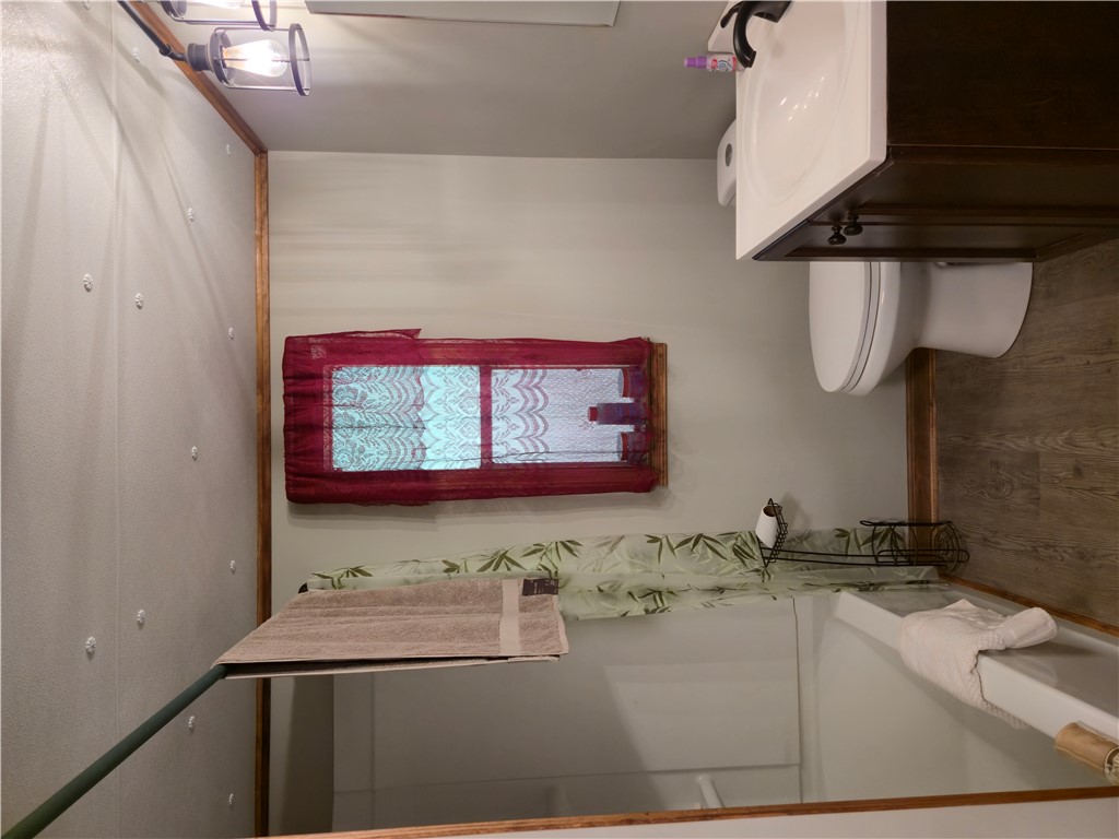 238 Forest Lane Starr, SC 29684 - Photo 9 of 11 A well-lit lavatory features a simple vanity, toilet, and bathtub with a window providing natural light.