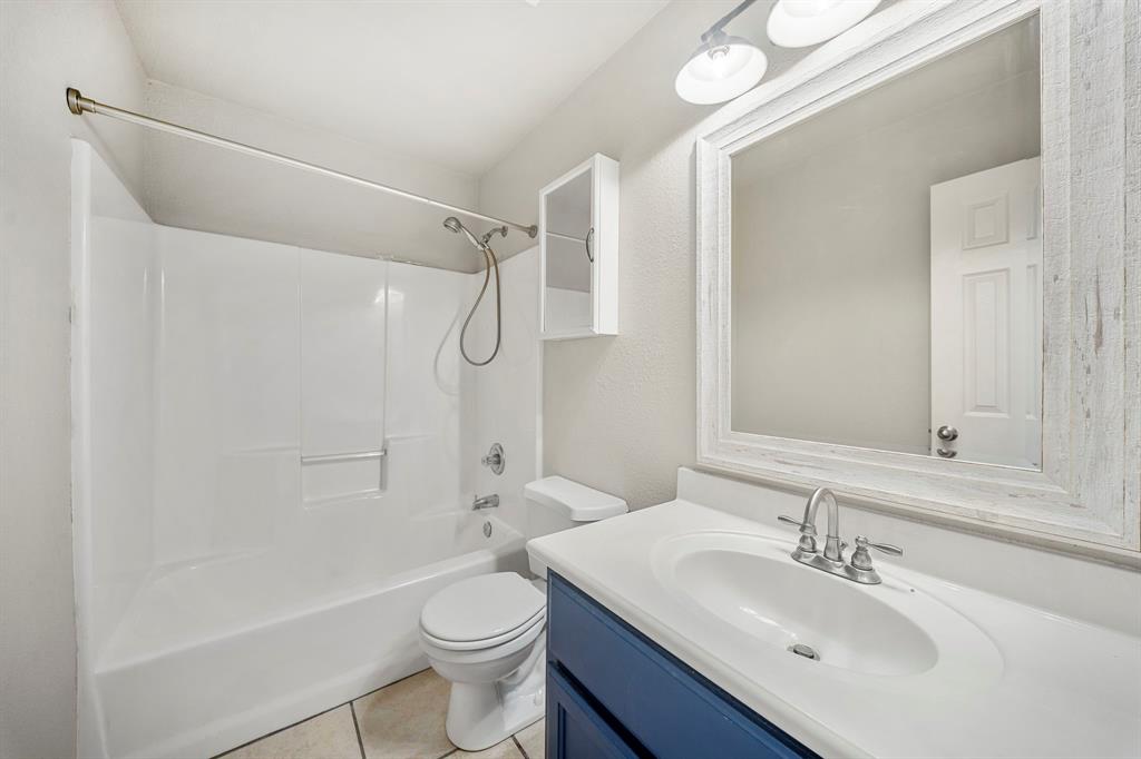 10620 Granada Drive Waco, TX 76708 - Photo 28 of 38 White shower/tub combination, single vanity with integrated sink, wood-finish mirror, and overhead vanity lighting