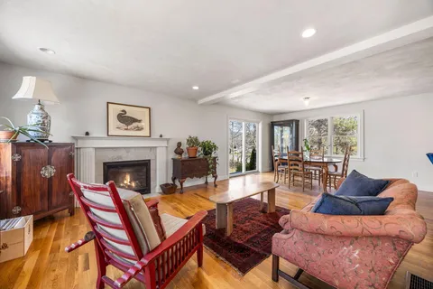 a living room with furniture a fireplace and a dining table with wooden floor