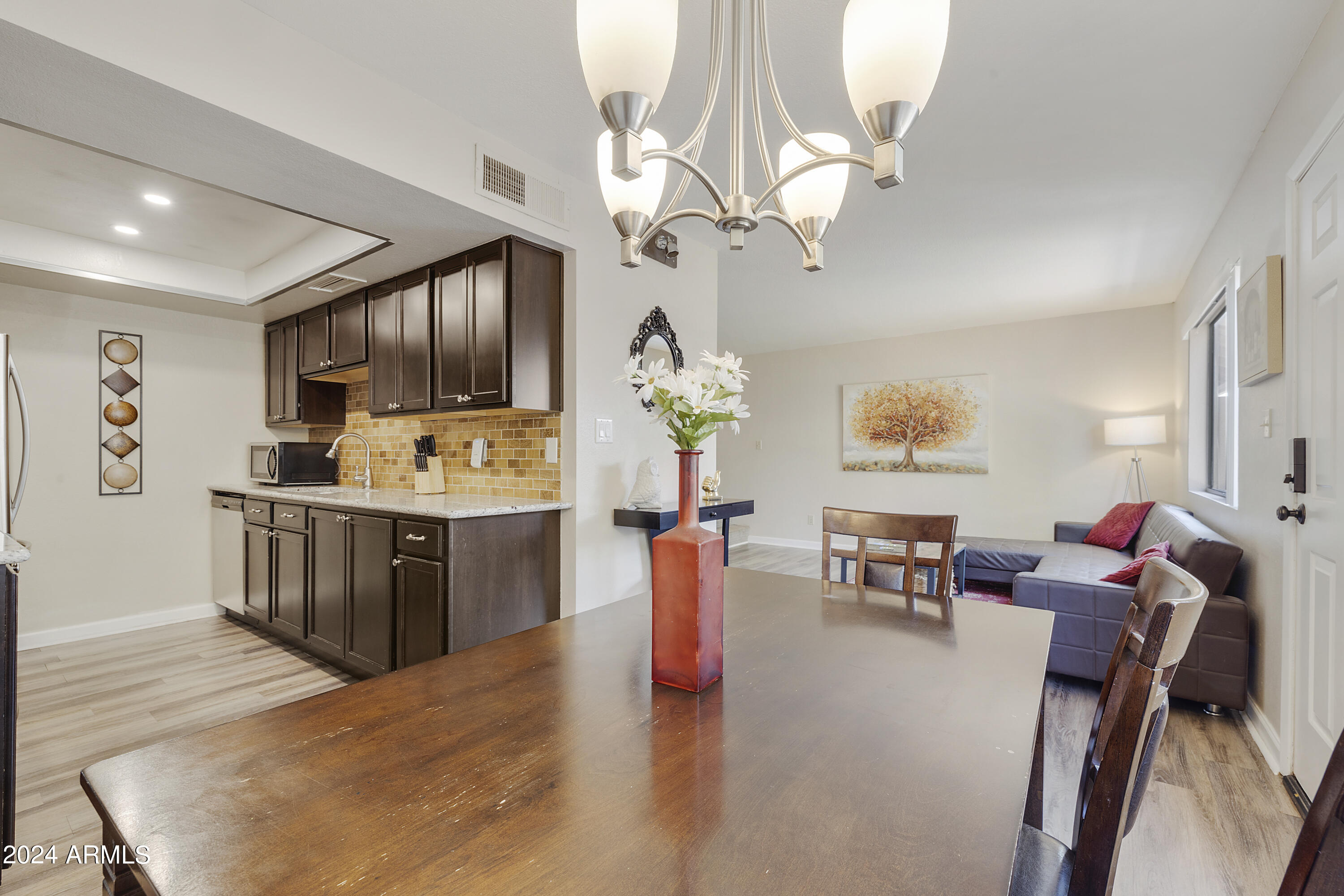 1223 North Granite Reef Road Scottsdale, AZ 85257 - Photo 23 of 35 a kitchen with stainless steel appliances kitchen island granite countertop a refrigerator a stove top oven a dining table and chairs with wooden floor