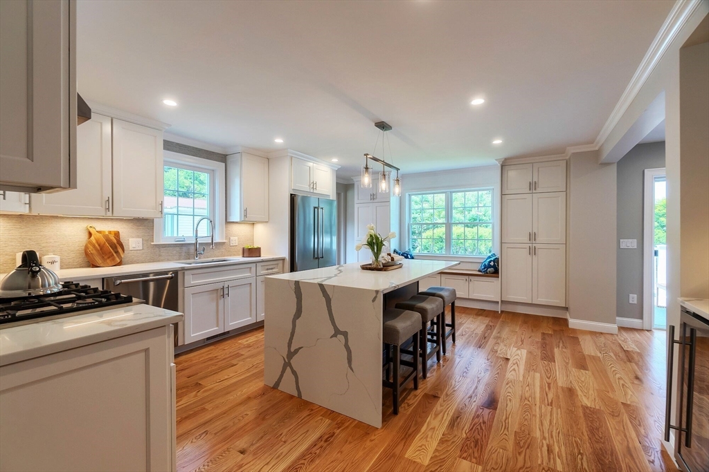 269 Dale Street, Unit 1 Waltham, MA 02451 - Photo 2 of 42 a kitchen with kitchen island granite countertop a stove a sink a refrigerator and white cabinets with wooden floor
