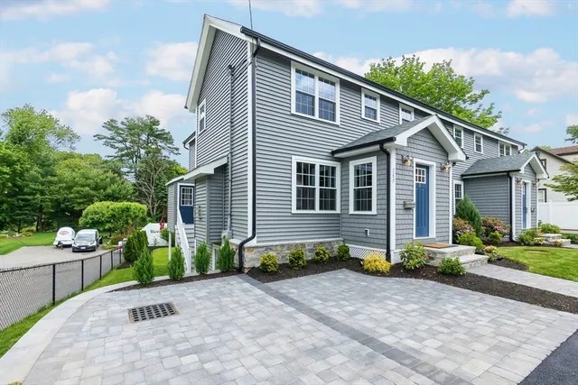 a front view of a house with a yard and potted plants