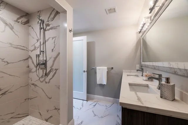 a bathroom with a sink and mirror with bathtub