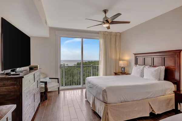 a bedroom with a large bed and a flat tv screen on dresser
