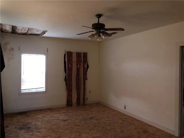 an empty room with a window and a ceiling fan