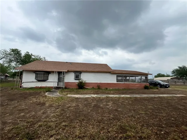 a view of a house with a yard and table and chairs under an umbrella