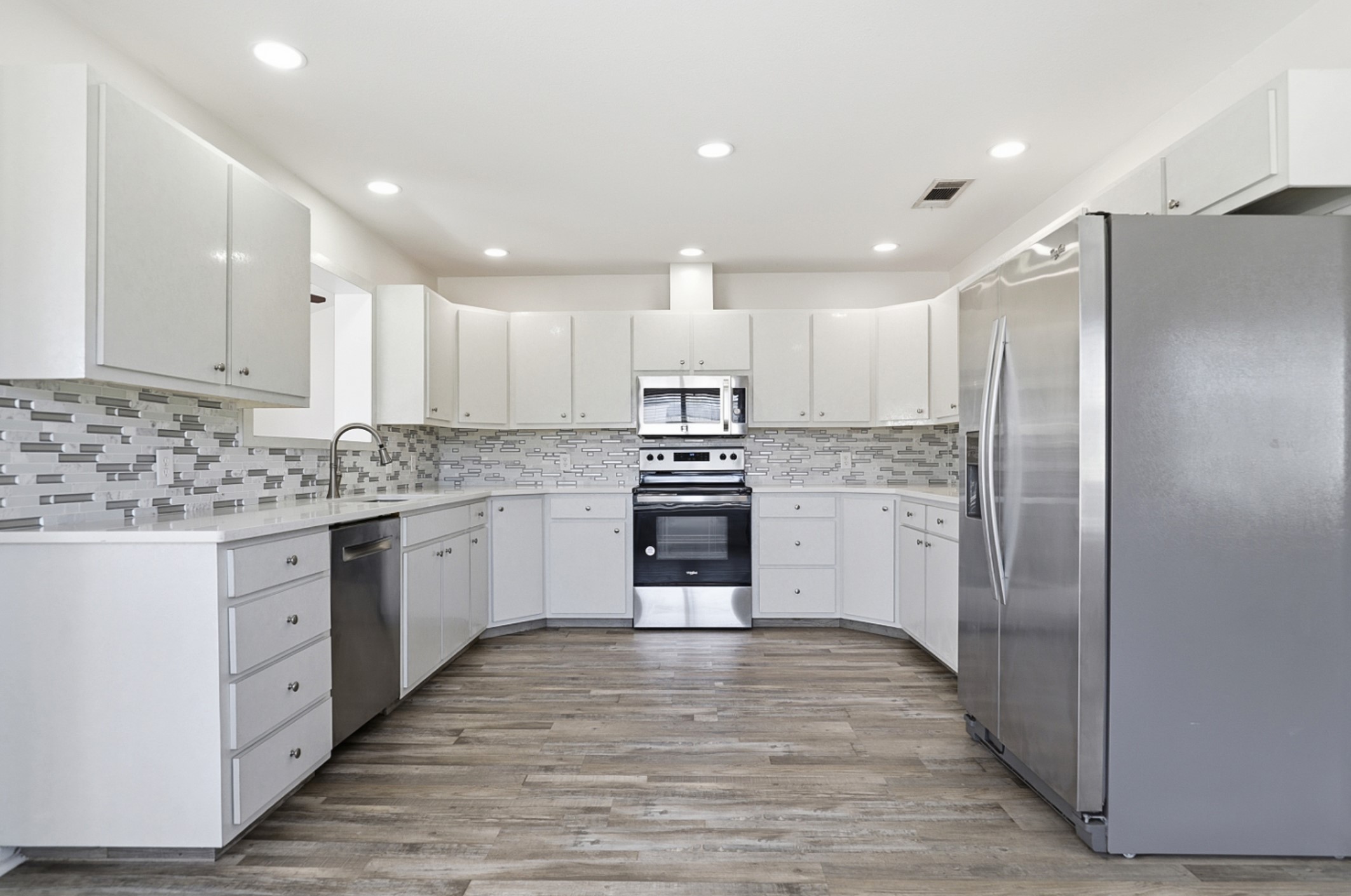 128 Skyview Terrace Leander, TX 78641 - Photo 8 of 23 Kitchen featuring stainless steel appliances, white cabinets, light wood-style floors, recessed lighting, and backsplash