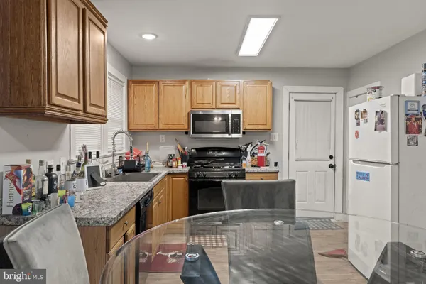 a kitchen with granite countertop a stove top oven a sink dishwasher and a refrigerator with wooden floor