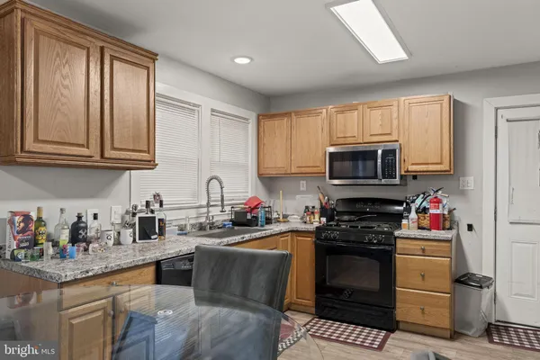 a kitchen with granite countertop a sink cabinets stainless steel appliances and a window