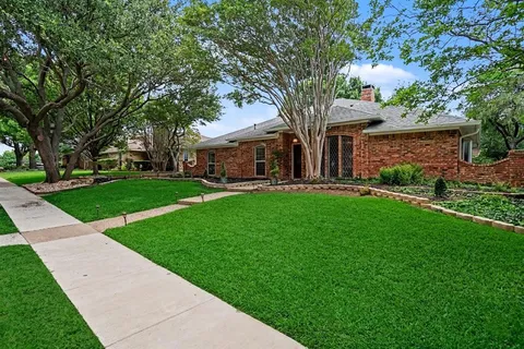 a front view of a house with a garden and trees
