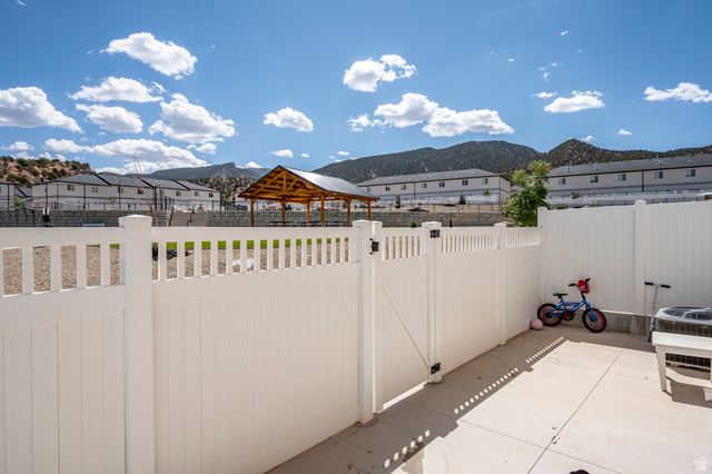 668 East Fiddlers Canyon Road, Unit 6 Cedar City, UT 84721 - Photo 29 of 36 Private patio space with a white privacy fence and gate, featuring concrete paving and mountain scenery in the background