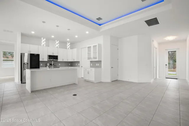 a large white kitchen with kitchen island white cabinets and stainless steel appliances
