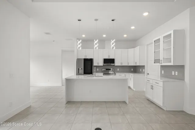 a large white kitchen with a refrigerator a stove top oven and white cabinets