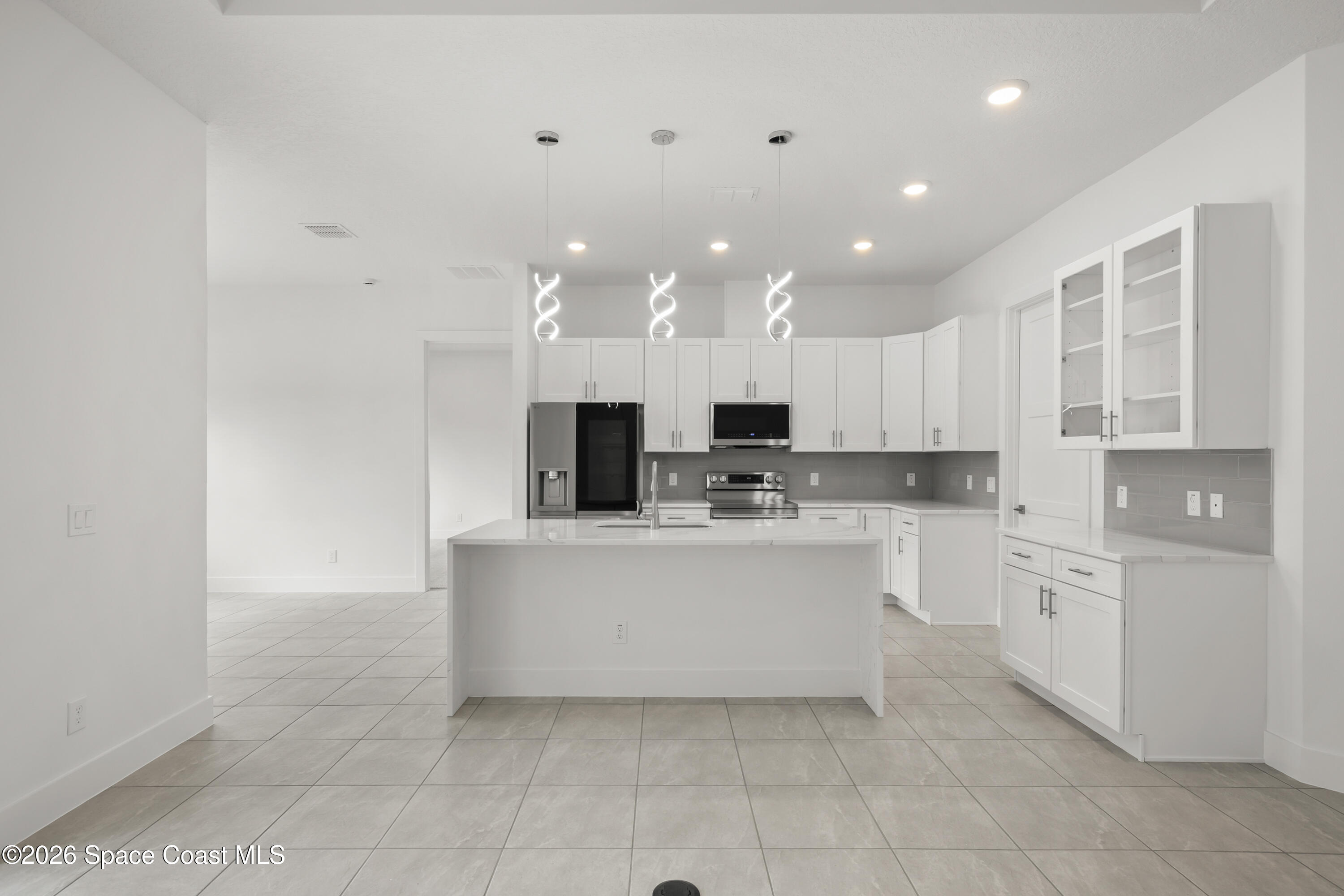 655 Vine Street Melbourne, FL 32904 - Photo 13 of 33 a large white kitchen with a refrigerator a stove top oven and white cabinets