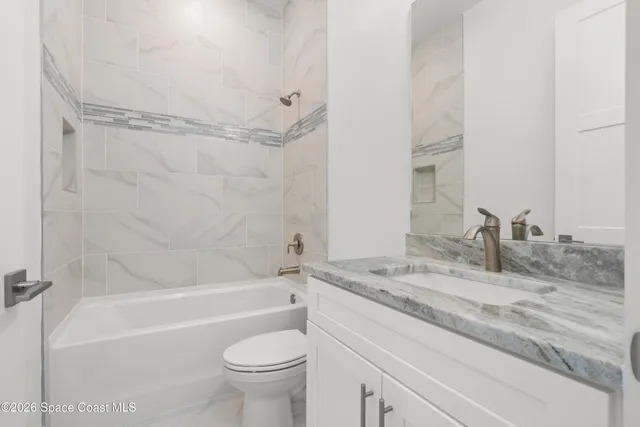 a bathroom with a granite countertop bathtub shower sink vanity and toilet