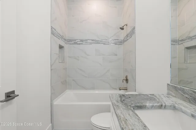 a bathroom with a granite countertop bathtub shower sink and toilet