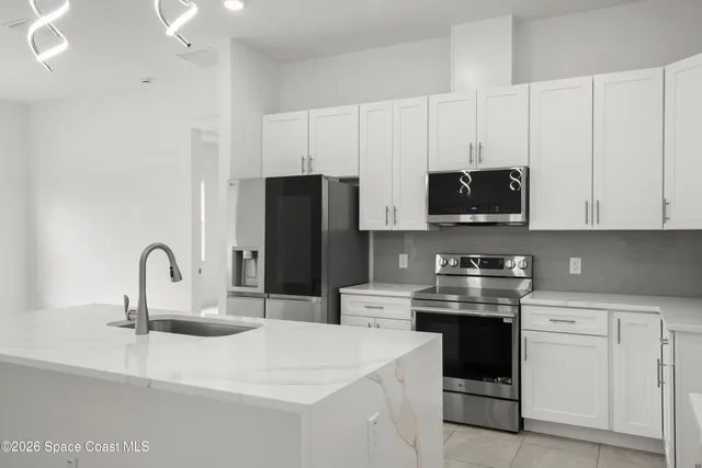 a kitchen with stainless steel appliances kitchen island a white stove top oven and white cabinets