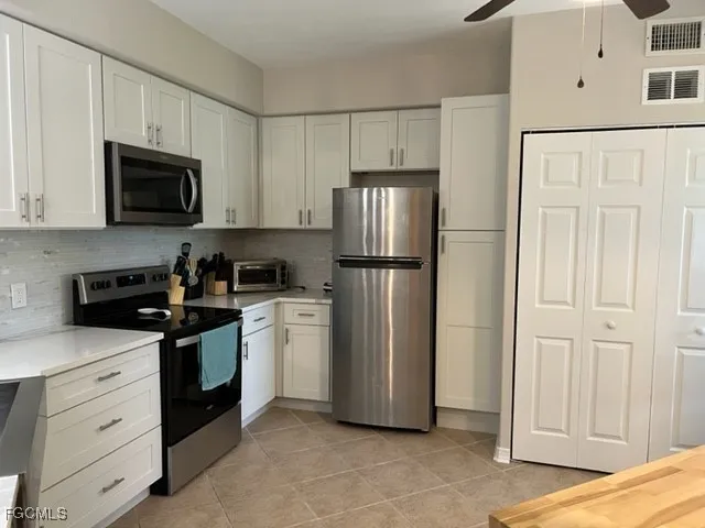 a kitchen with white cabinets and stainless steel appliances
