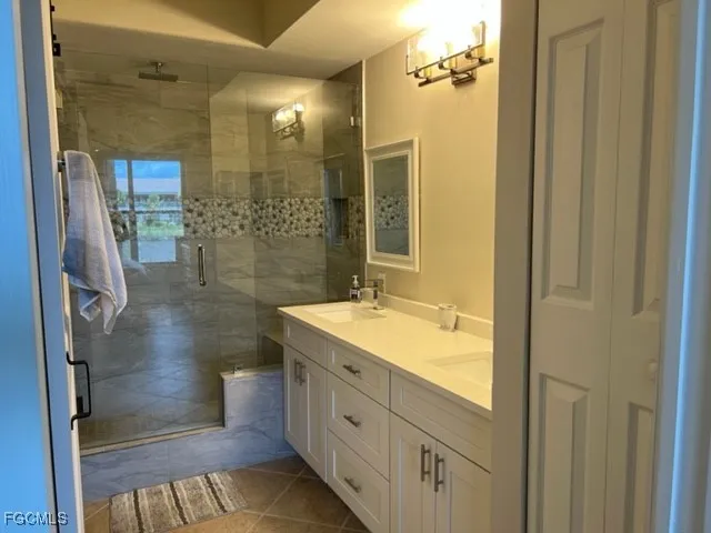 a bathroom with a granite countertop sink a mirror and a shower