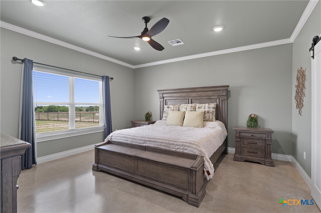 15073 Armstrong Ests Road Salado, TX 76571 - Photo 23 of 44 a bedroom with a large bed and a chandelier