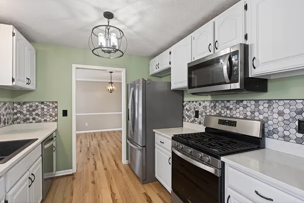 a kitchen with stainless steel appliances a sink a stove top oven a counter space and cabinets