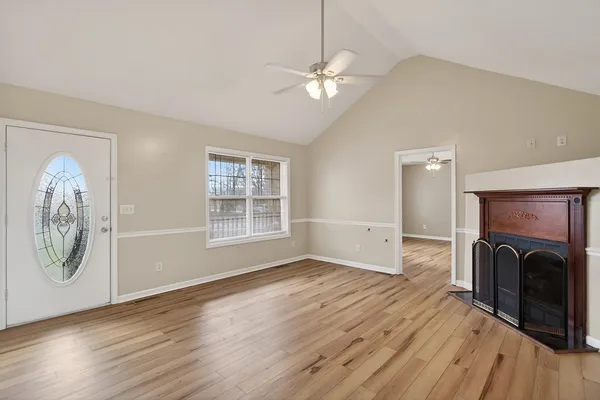 an empty room with wooden floor fireplace and windows