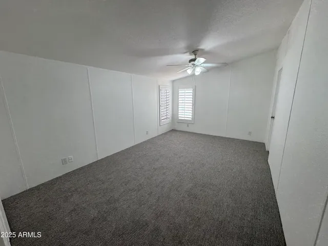 an empty room with windows and fan