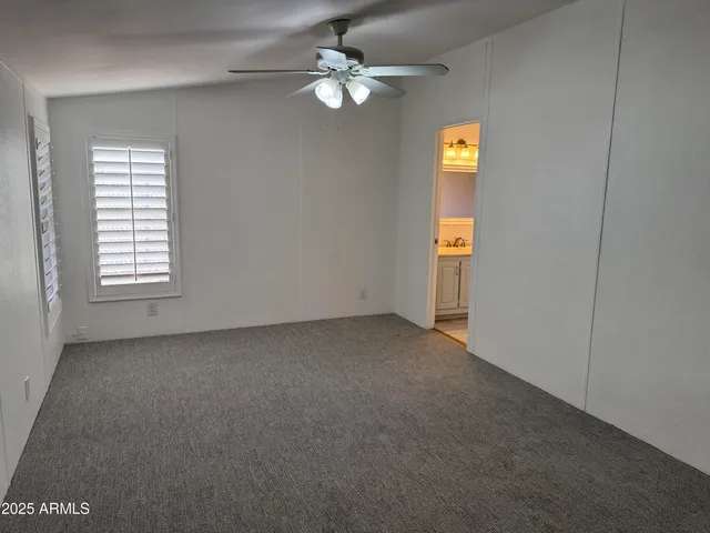 an empty room with windows and fan