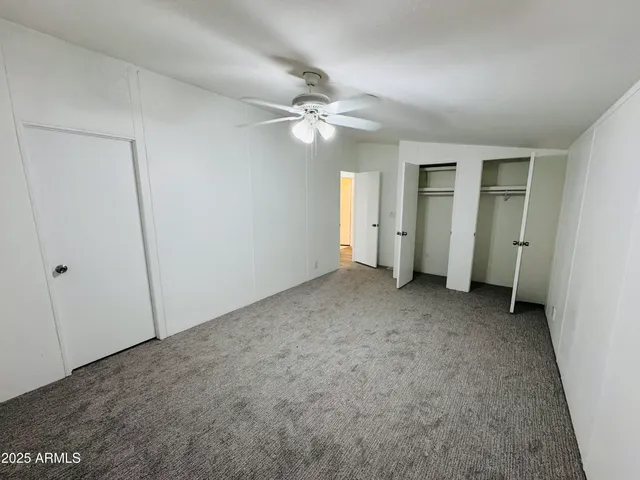 an empty room with closet and a ceiling fan