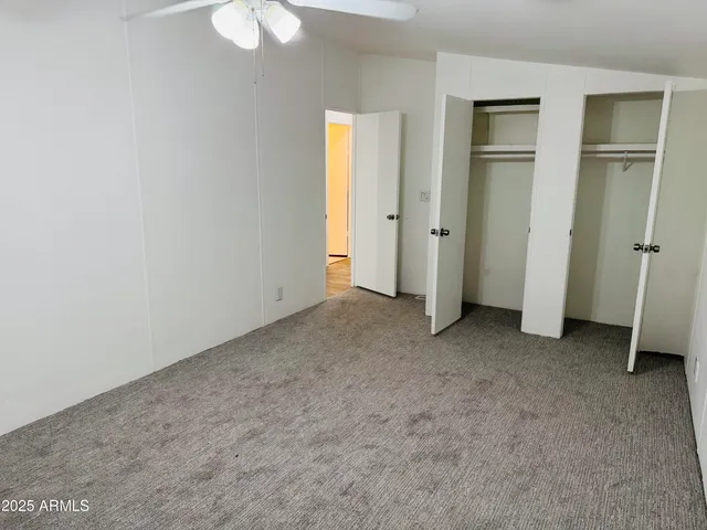 an empty room with closet and a chandelier fan