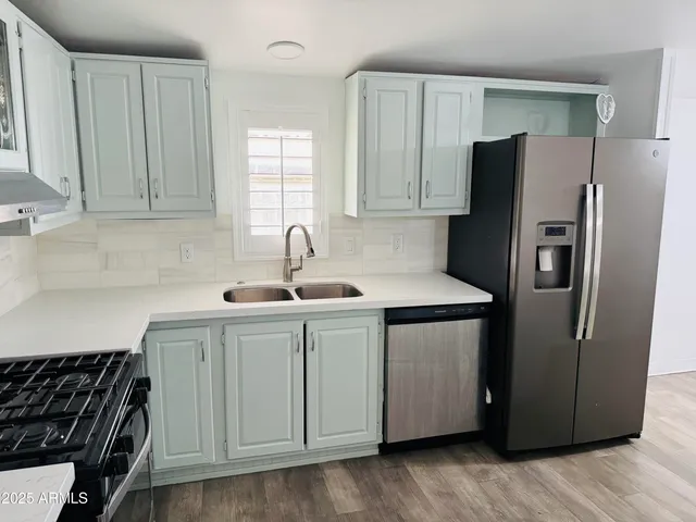 a kitchen with stainless steel appliances granite countertop a refrigerator a sink and white cabinets