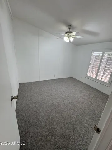 an empty room with windows and ceiling fan