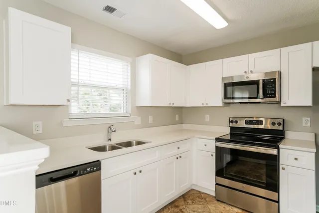 a kitchen with granite countertop a stove a sink and a microwave