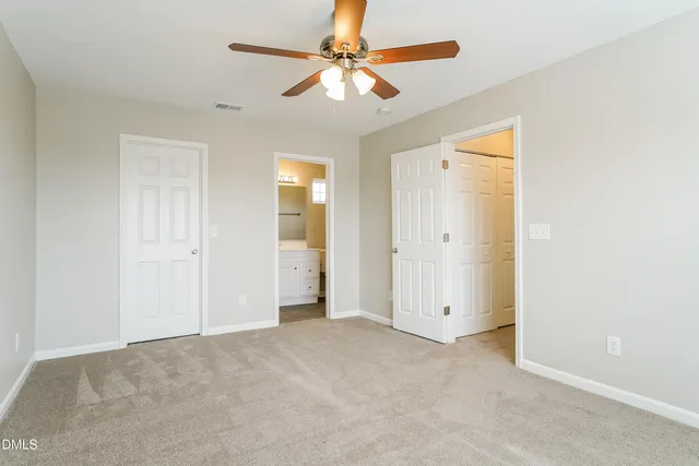 an empty room with closet and a ceiling fan
