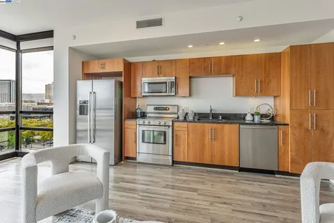 a kitchen with stainless steel appliances granite countertop a refrigerator a stove and a wooden floors