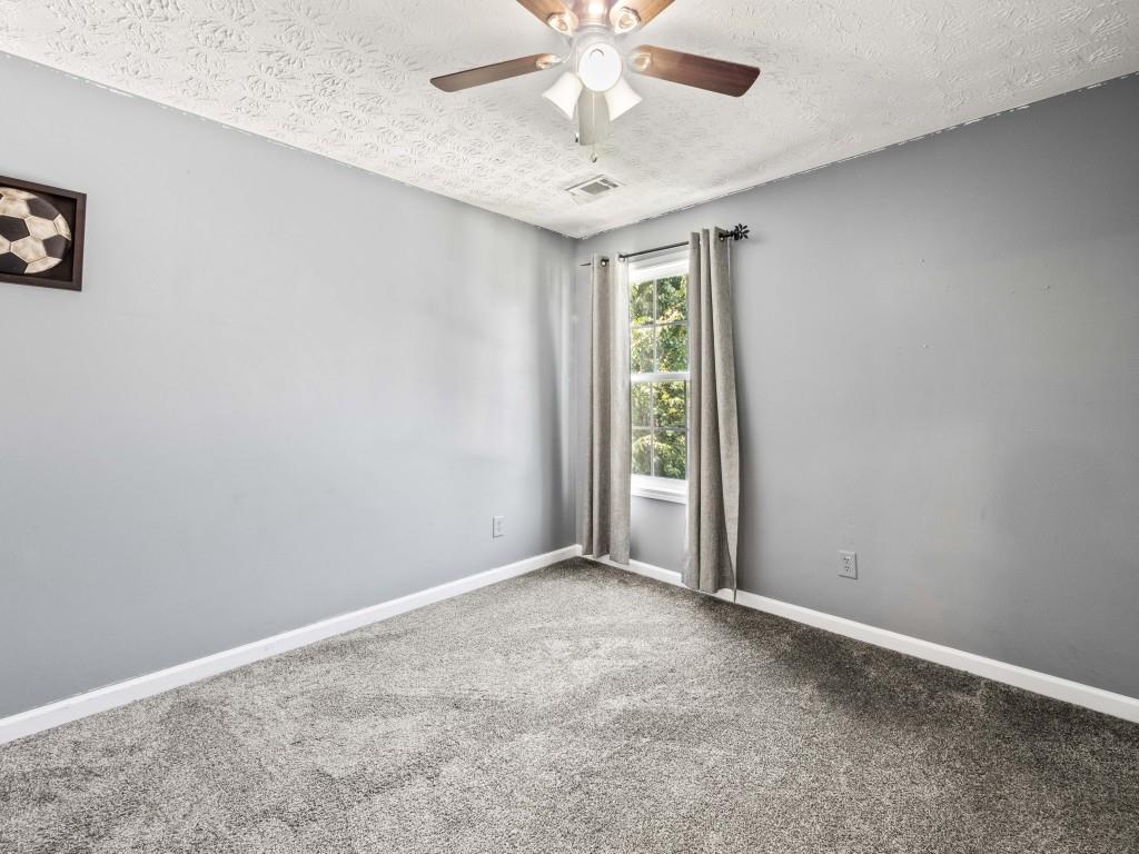 95 Ridge Water Lane Dawsonville, GA 30534 - Photo 24 of 45 an empty room with a chandelier fan and windows