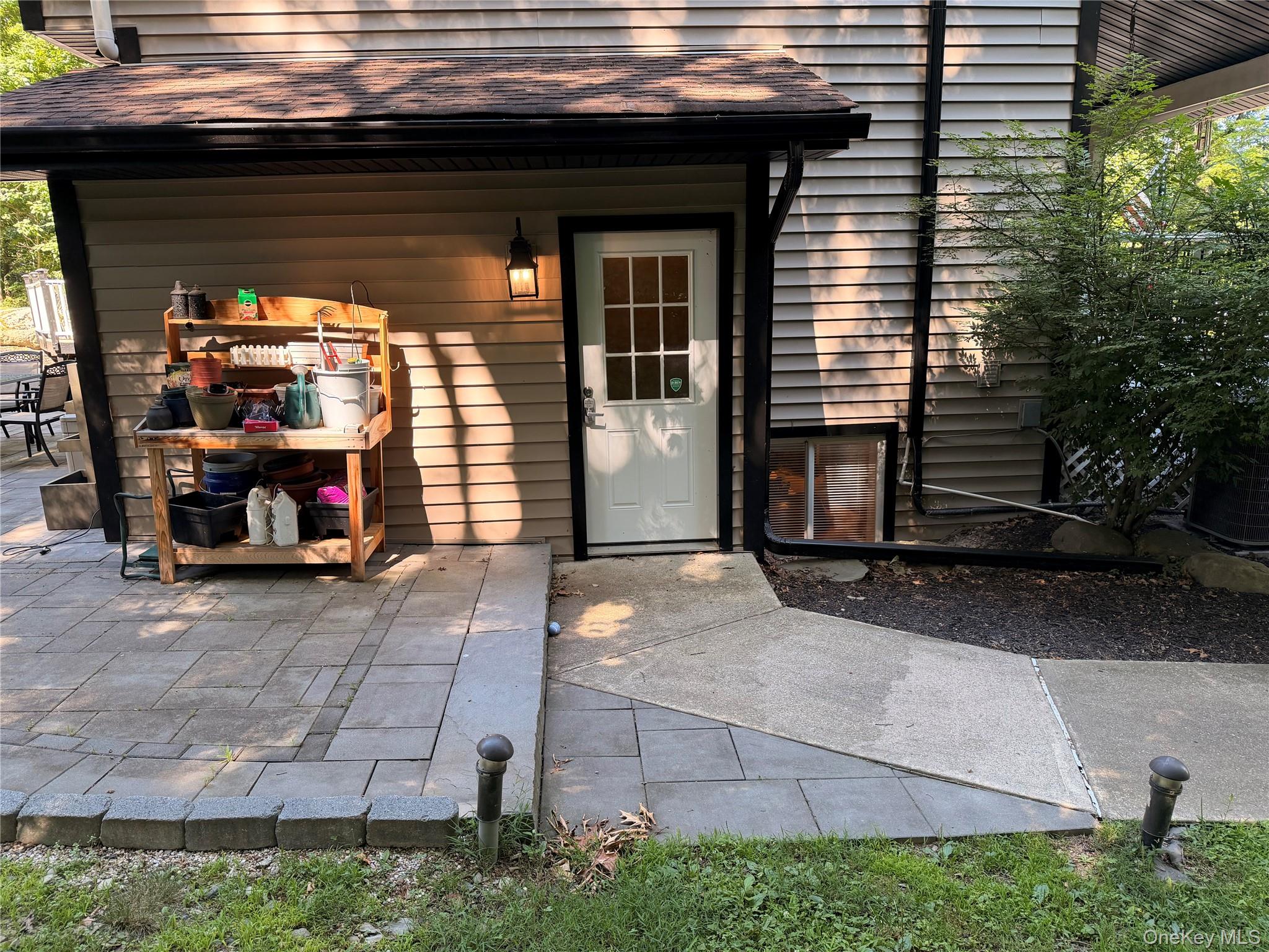 157 Brewer Road, Unit 1A Newburgh, NY 12550 - Photo 1 of 8 Outdoor paver patio with a concrete walkway, exterior wall light fixture, and a white door with window panes