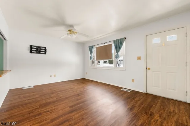 an empty room with wooden floor chandelier and windows