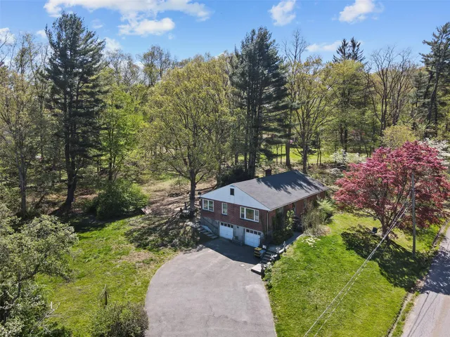 a view of a house with a big yard and large trees