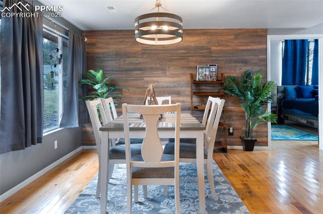 608 Slater Creek Road Guffey, CO 80820 - Photo 28 of 47 Dining space with wooden walls, light wood finished floors, and a chandelier