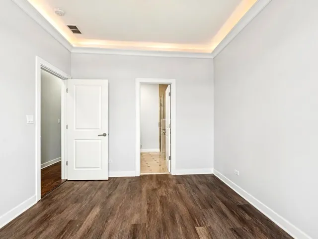 a view of an empty room with wooden floor and closet