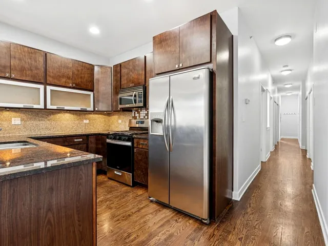 a kitchen with stainless steel appliances granite countertop a refrigerator a sink and a stove top oven