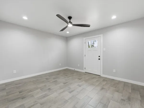 an empty room with ceiling fan and wooden floor