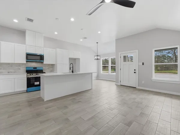 an empty room with windows and ceiling fan